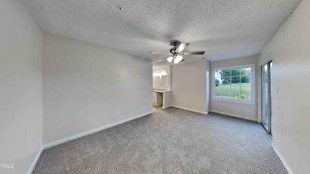 empty room with a ceiling fan, light carpet, a textured ceiling, and baseboards