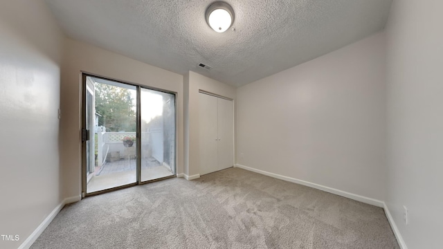 spare room featuring light carpet, visible vents, baseboards, and a textured ceiling