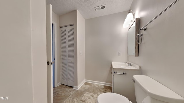 bathroom with visible vents, toilet, a textured ceiling, vanity, and a closet