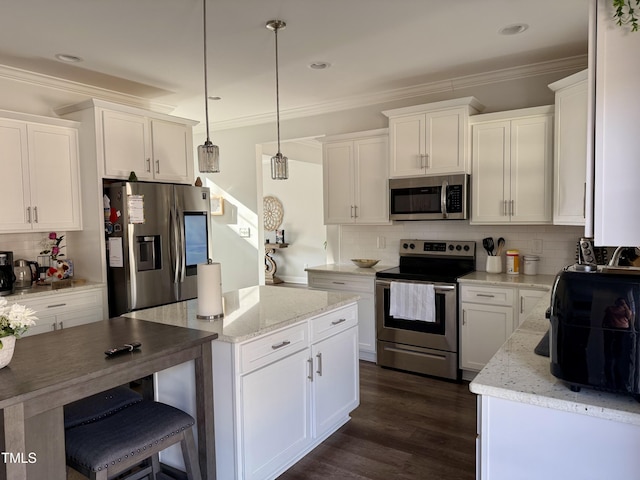 kitchen featuring appliances with stainless steel finishes, a kitchen island, white cabinetry, and crown molding