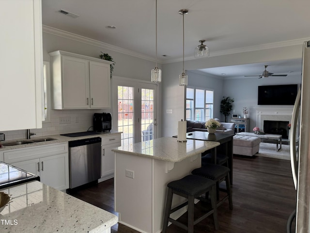 kitchen featuring stainless steel appliances, dark wood-type flooring, a kitchen island, a sink, and visible vents