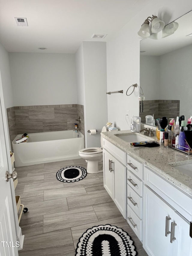 bathroom featuring double vanity, a garden tub, visible vents, and a sink