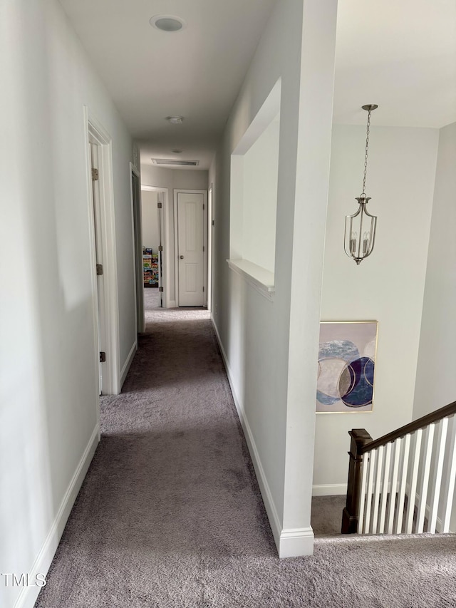 corridor with a chandelier, carpet, and baseboards