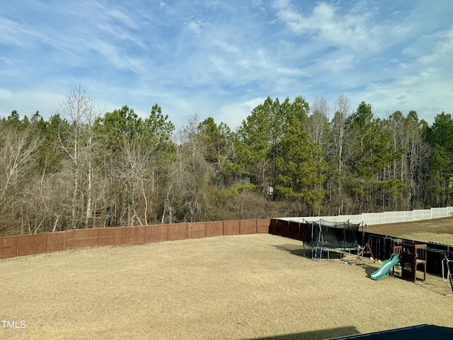 view of yard featuring a trampoline and fence