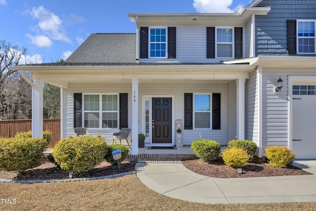 view of front of house featuring a garage, a porch, and fence