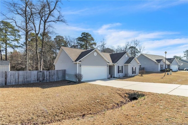 ranch-style home featuring an attached garage, driveway, a front lawn, and fence