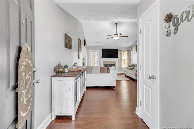 hallway featuring dark wood-style floors, baseboards, and vaulted ceiling