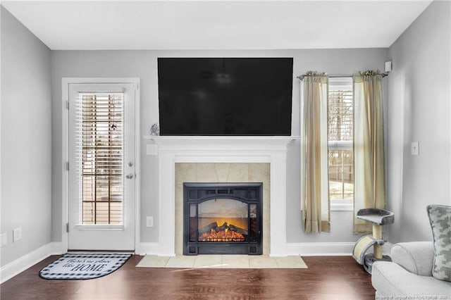 living room with wood finished floors, baseboards, and a tile fireplace