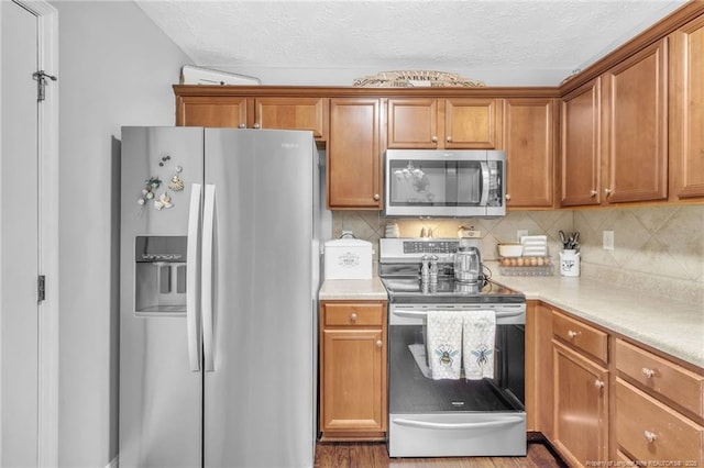 kitchen featuring brown cabinets, tasteful backsplash, appliances with stainless steel finishes, and light countertops