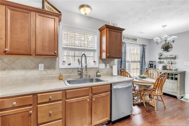 kitchen featuring brown cabinetry, a sink, light countertops, dishwasher, and tasteful backsplash