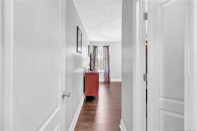 hallway featuring baseboards and dark wood-style flooring