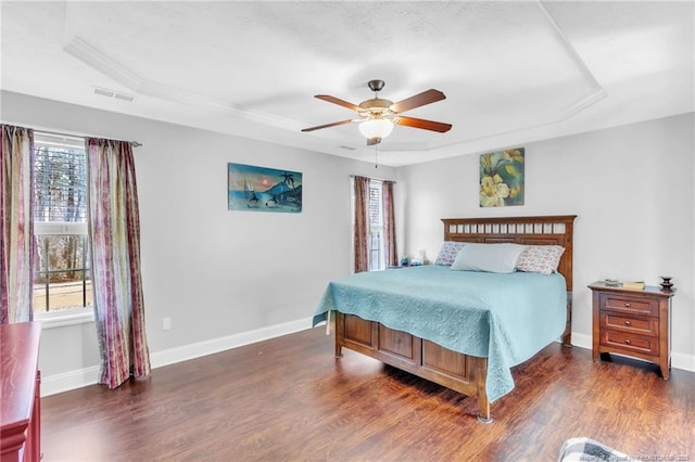 bedroom with baseboards, a raised ceiling, and wood finished floors