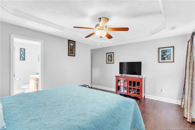 bedroom with visible vents, dark wood-type flooring, a raised ceiling, crown molding, and baseboards