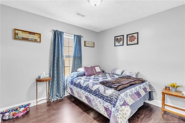 bedroom featuring visible vents, baseboards, and wood finished floors