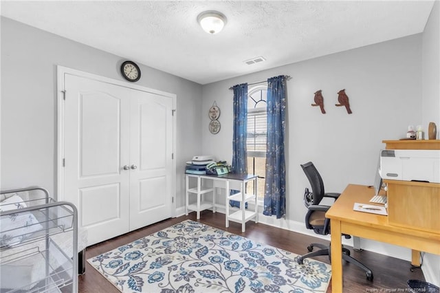 office area featuring visible vents, a textured ceiling, baseboards, and wood finished floors