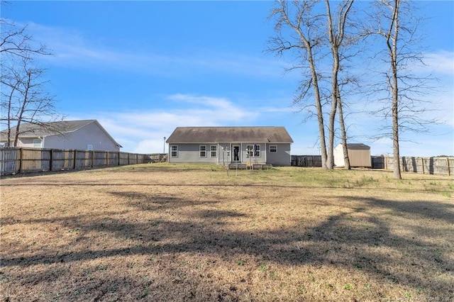 back of property with a storage shed, an outdoor structure, a yard, and a fenced backyard