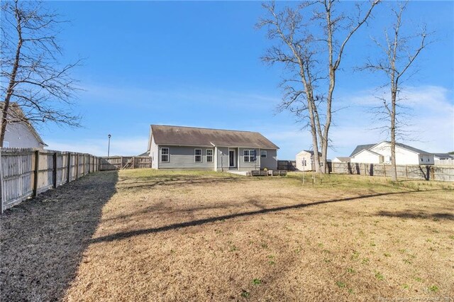 back of house with a fenced backyard and a yard