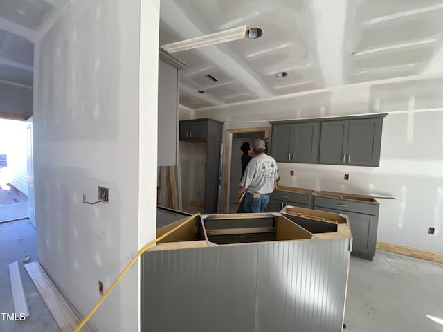 kitchen featuring baseboards, concrete floors, and gray cabinetry