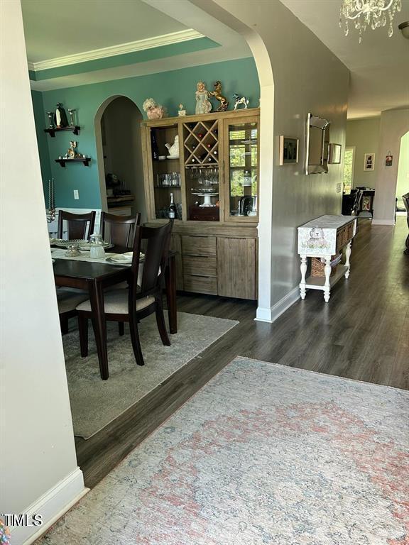 office with arched walkways, ornamental molding, dark wood-style floors, and baseboards