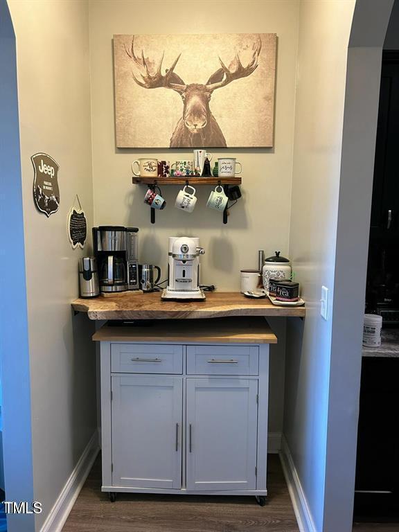 bar featuring dark wood-style floors, a dry bar, and baseboards