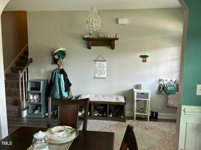 dining space featuring arched walkways, stairway, baseboards, and wood finished floors