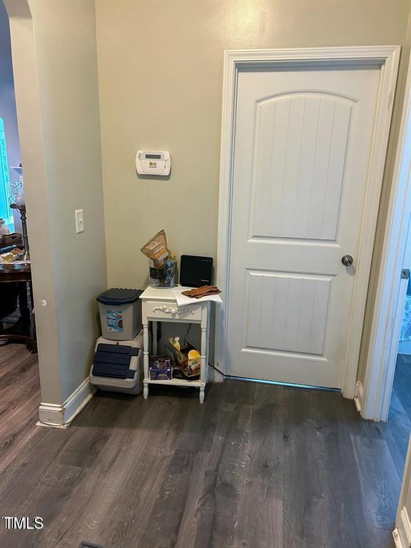 doorway to outside with arched walkways, dark wood-type flooring, and baseboards