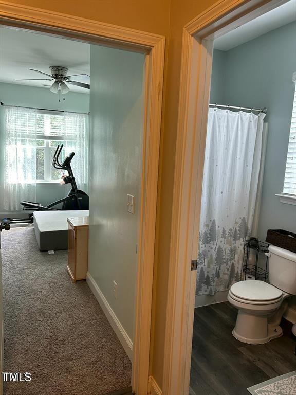 bathroom with ceiling fan, wood finished floors, toilet, and baseboards