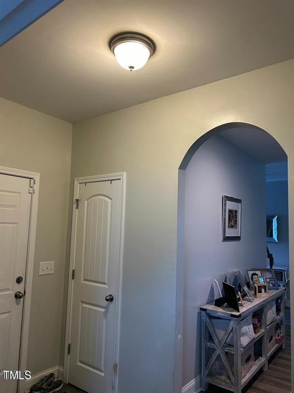 hall featuring baseboards, arched walkways, and dark wood-style flooring