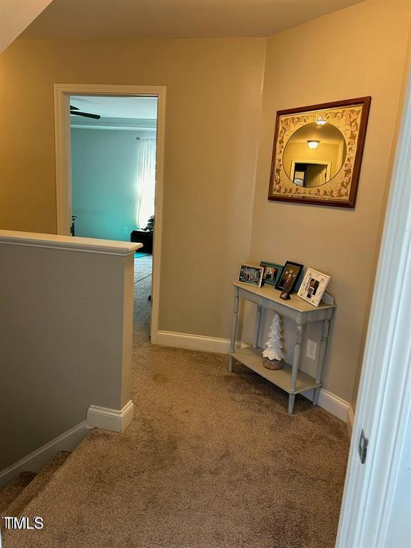 hallway with an upstairs landing, carpet flooring, and baseboards