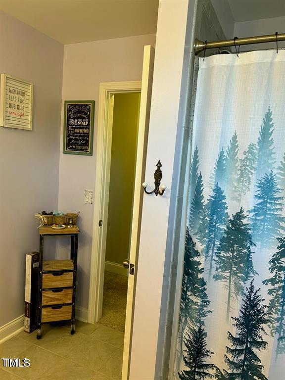 full bath with a shower with curtain, baseboards, and tile patterned floors