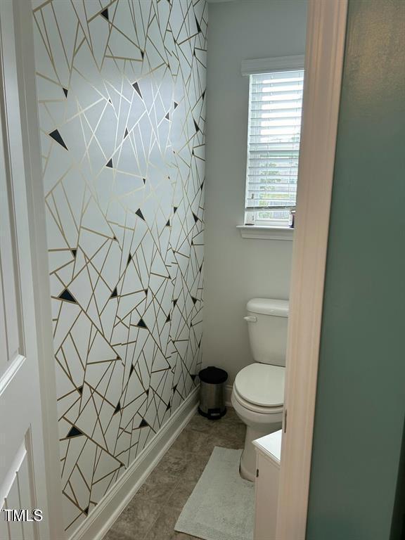 bathroom with toilet, tile patterned flooring, vanity, and baseboards