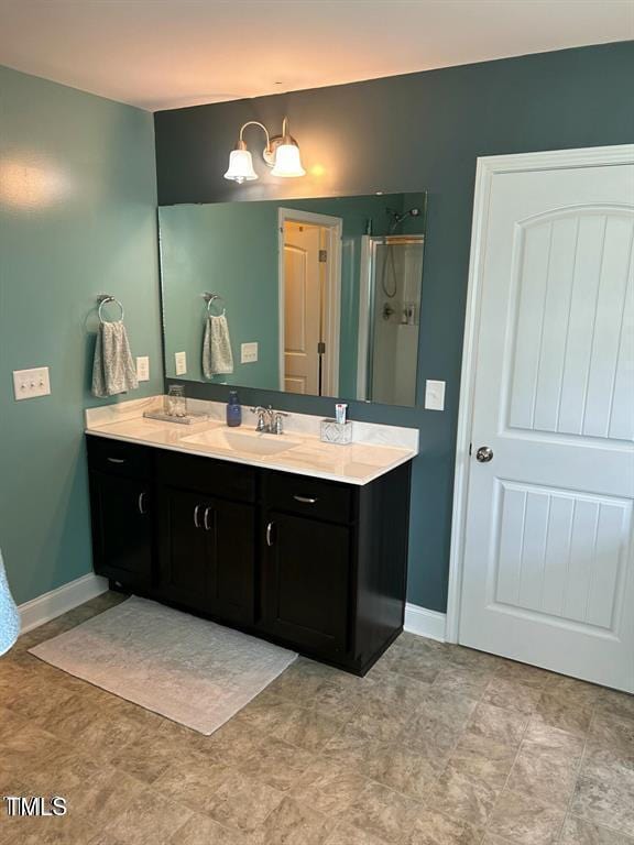 full bathroom featuring a stall shower, baseboards, and vanity