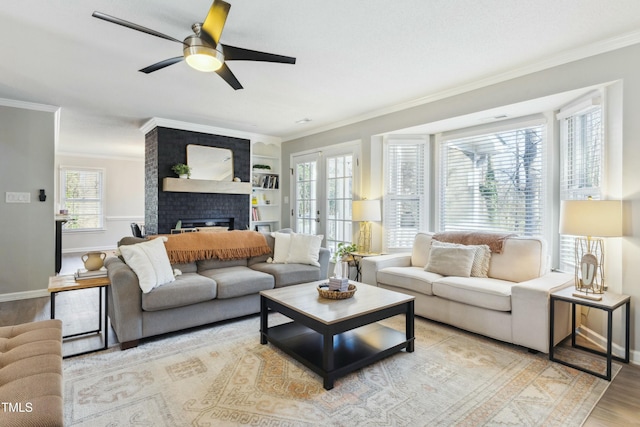 living area featuring a brick fireplace, baseboards, ornamental molding, and wood finished floors