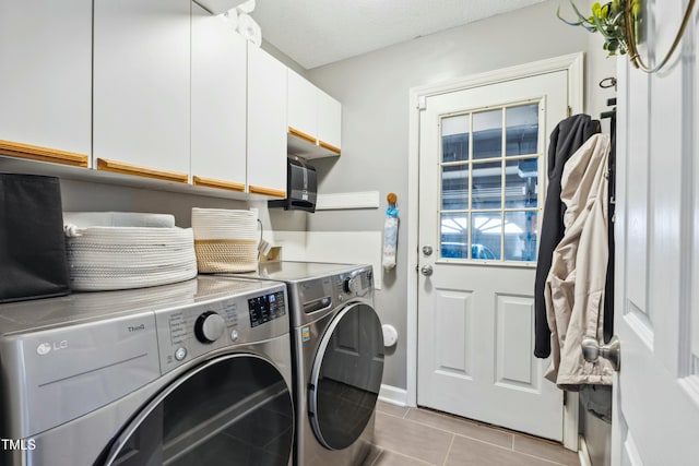 clothes washing area featuring a textured ceiling, light tile patterned flooring, washing machine and dryer, and cabinet space