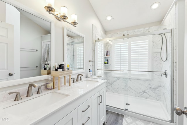 full bath with double vanity, a marble finish shower, a sink, and recessed lighting