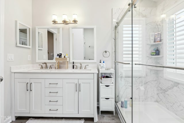 bathroom with double vanity, a sink, and a marble finish shower