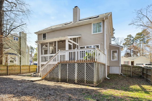 back of house featuring a fenced backyard, a sunroom, stairs, a wooden deck, and a chimney