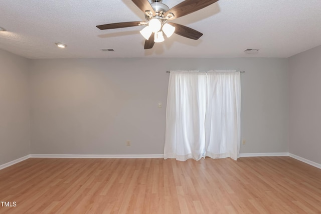 spare room featuring visible vents, baseboards, light wood-style flooring, and a textured ceiling