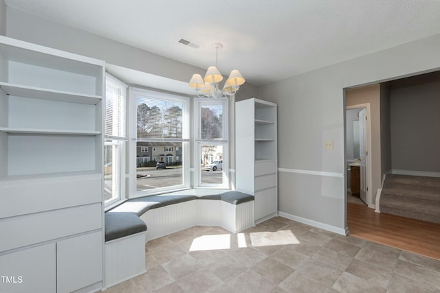 unfurnished dining area with stairs, visible vents, baseboards, and an inviting chandelier