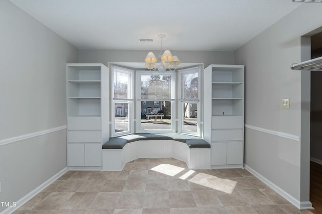 unfurnished dining area featuring an inviting chandelier, baseboards, and visible vents