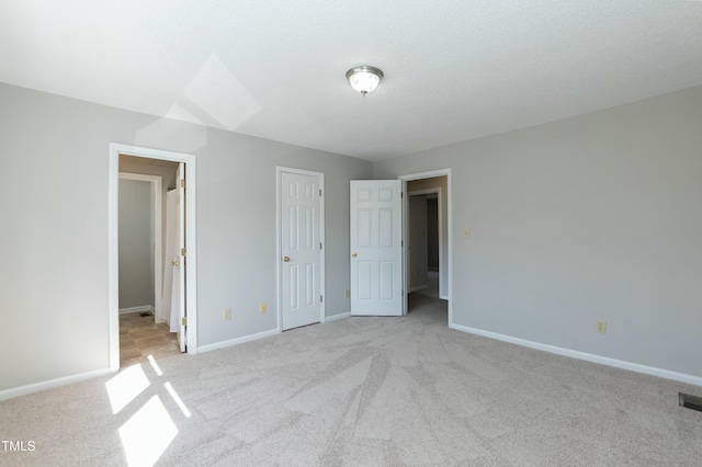 unfurnished bedroom with light carpet, a textured ceiling, and baseboards