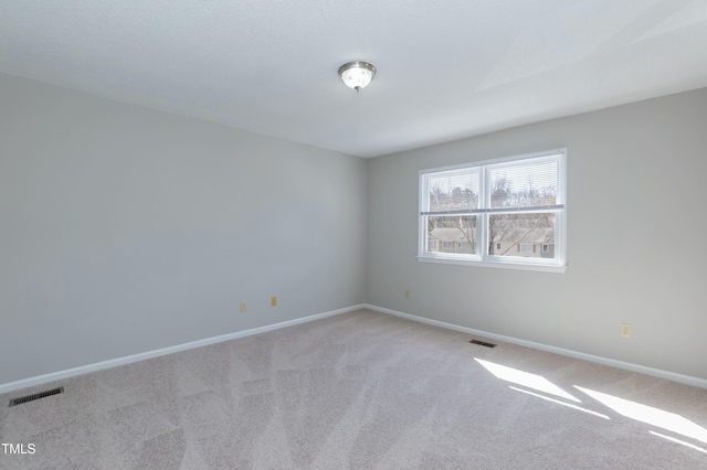 empty room featuring light carpet, baseboards, and visible vents