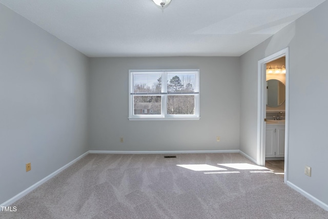 spare room featuring baseboards, visible vents, and light colored carpet