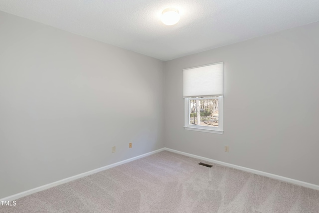 empty room featuring carpet, visible vents, a textured ceiling, and baseboards