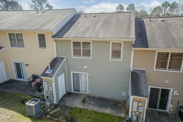 rear view of property featuring a patio, central AC unit, and a shingled roof