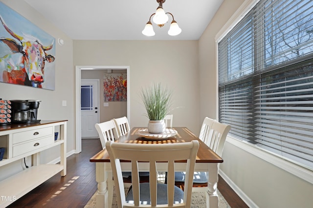 dining room with dark wood-type flooring, a notable chandelier, and baseboards