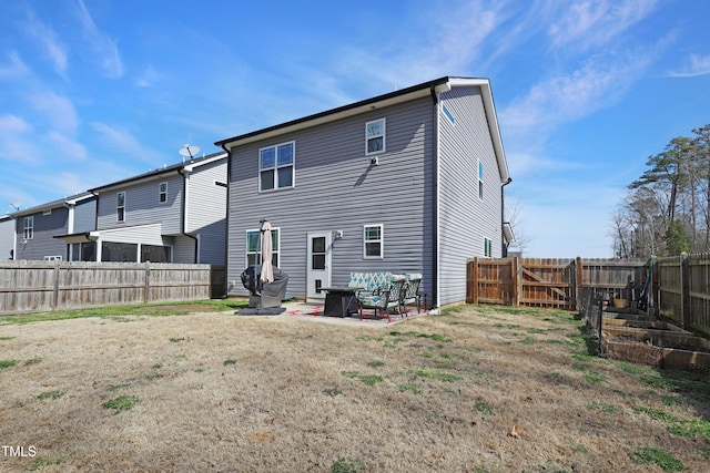 rear view of house featuring a fenced backyard, a lawn, and a patio