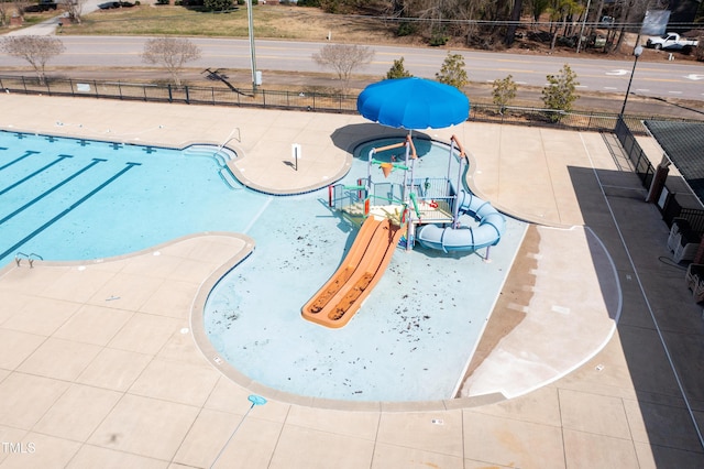 pool with a patio area, fence, and a water play area