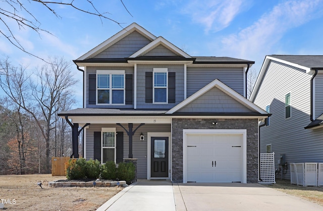 craftsman-style home featuring an attached garage, concrete driveway, a porch, and stone siding