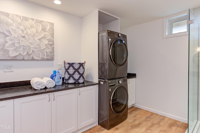 washroom with recessed lighting, cabinet space, light wood-style floors, stacked washer / dryer, and baseboards